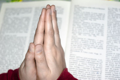 Close-up of human hand praying against book