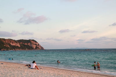 People at beach against sky