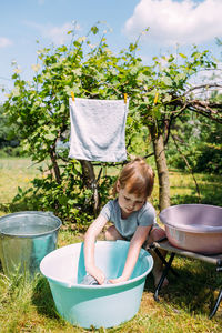 Little preschool girl helps with laundry. child washes clothes in garden