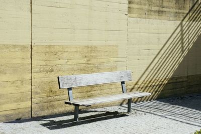 Empty wooden bench against wall