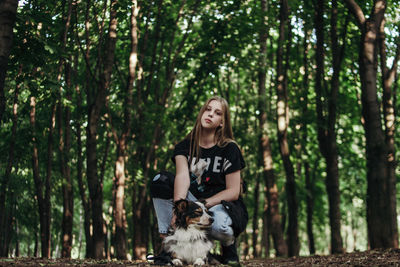 Portrait of teenage girl with dog against trees