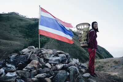 Flag standing on rock by mountain against sky