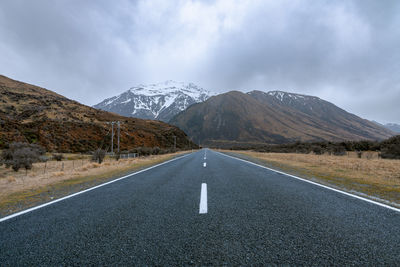 Empty road by mountains against sky