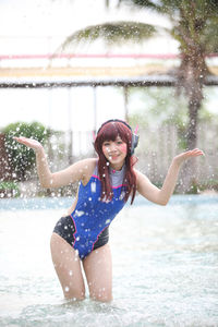 Portrait of young woman standing in water