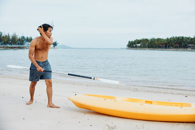 Rear view of shirtless man jumping in sea against sky