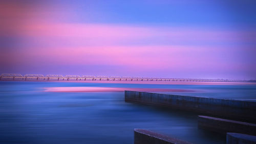 Bridge over sea against sky during sunset