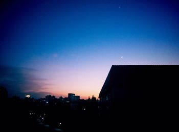 Silhouette buildings against blue sky at dusk