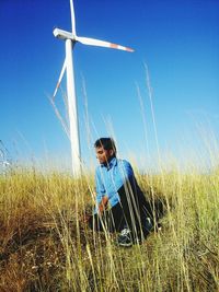 Traditional windmill on field against clear blue sky