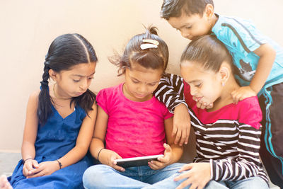 Friends looking away while sitting on mobile phone