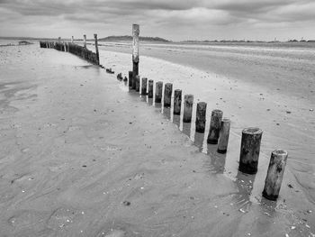 Wooden posts on beach against sky