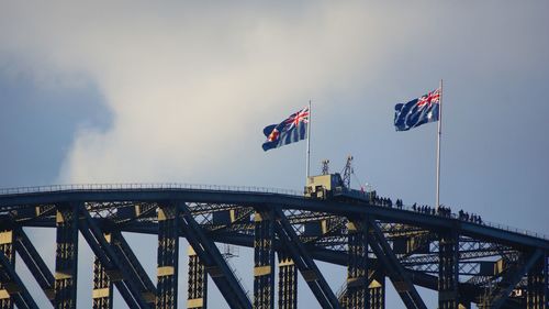 Low angle view of crane against bridge against sky