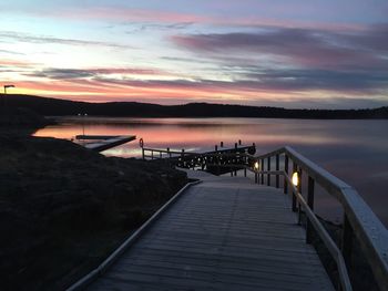 Pier over lake against sky during sunset