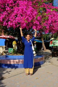Portrait of happy woman standing on pink flowering plants