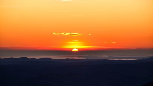 Scenic view of silhouette mountains against orange sky