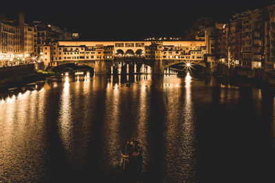 Illuminated bridge over river in city against sky at night