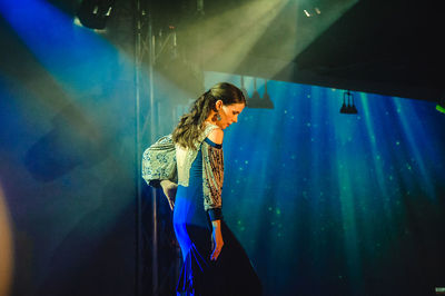 Young woman standing against curtain