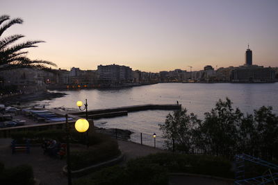 River by illuminated city against clear sky