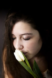 Close-up portrait of a beautiful young woman over black background