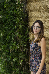 Portrait of young woman standing by plants