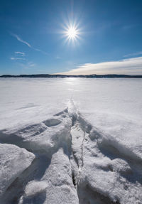 Scenic view of snow covered landscape against bright sun