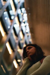 Low angle view of thoughtful young woman standing in illuminated room