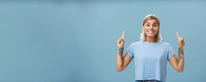 Portrait of young woman standing against blue background