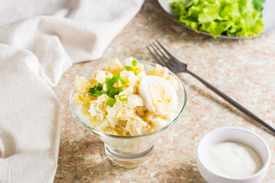 Potato salad with boiled egg, green onion and mayonnaise in a bowl on the table