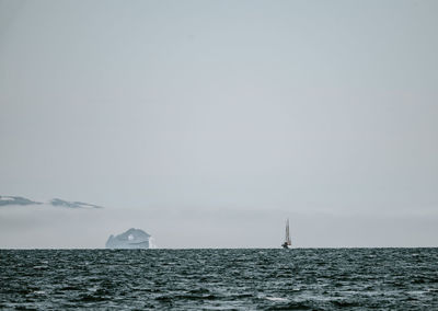 Sailboat in sea against clear sky