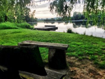 Bench by lake against sky