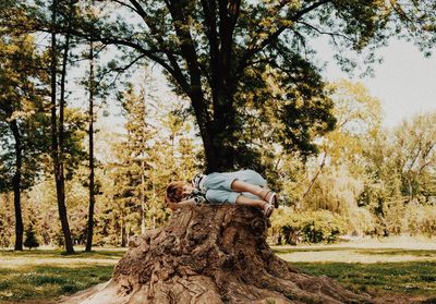 Woman lying on tree stump at field