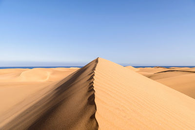 Scenic view of desert against clear blue sky