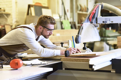 Carpenter measuring wooden boards in his workshop