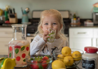 Portrait of cute girl drinking juice in kitchen at home