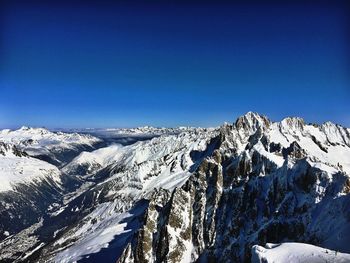 Scenic view of snowcapped mountains against clear blue sky