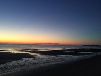 Scenic view of beach against clear sky during sunset