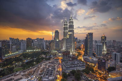 Illuminated cityscape against cloudy sky