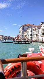 Boats in canal by buildings against sky in city