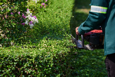 Worker in protective clothing with a lawn mower in hands working in workplace