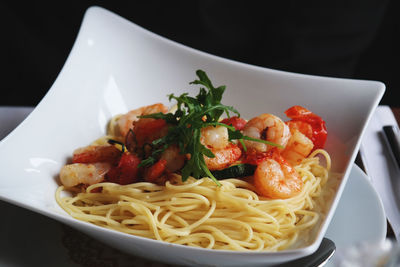 Prawns and spaghetti served in plate against black background