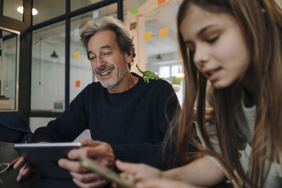 Casual senior buisinessman and girl using tablet and smartphone in office