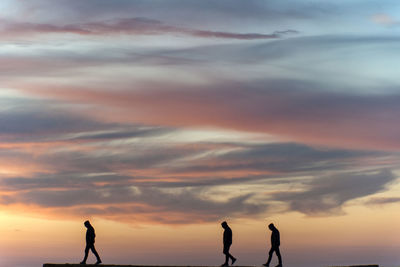 Silhouette people standing against sky during sunset