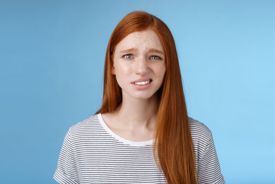 Portrait of smiling young woman against blue background