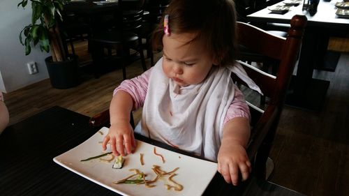 High angle view of cute girl eating food while sitting at home