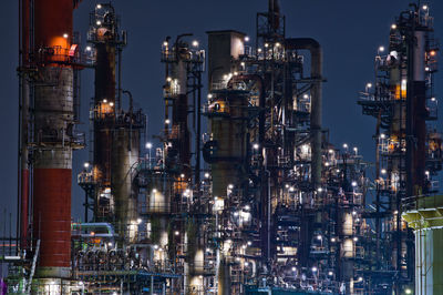 Illuminated factory against sky at night