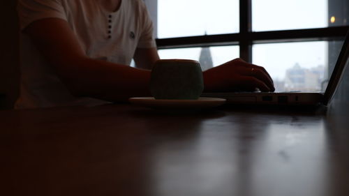 Midsection of woman holding smart phone on table