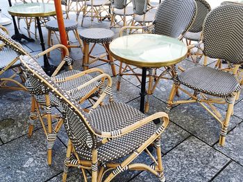 Close-up of empty chairs and tables at sidewalk cafe