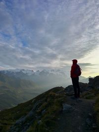 Rear view of man standing on mountain against sky