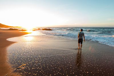 Full length of man on beach against sky during sunset