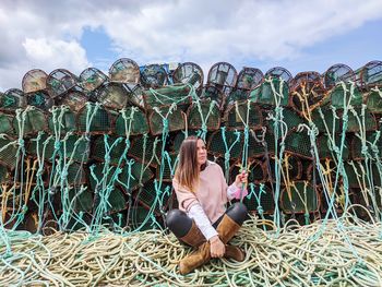 Woman sitting by plants against sky