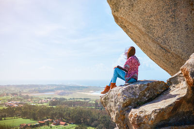 Man looking at rock formation against sky